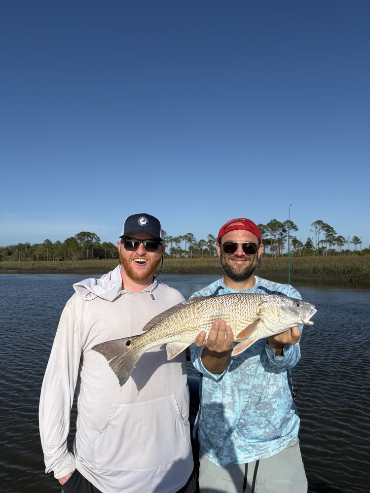 Two friends on the skiff with a redfish