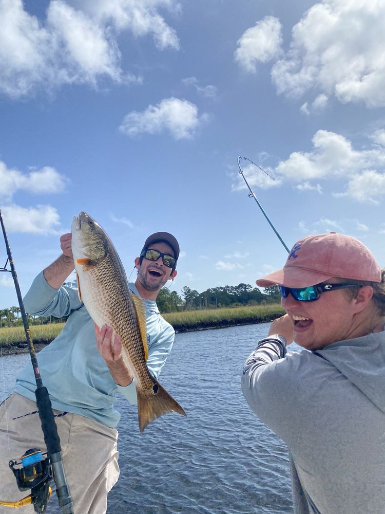 Anglers laughing on the skiff with a redfish