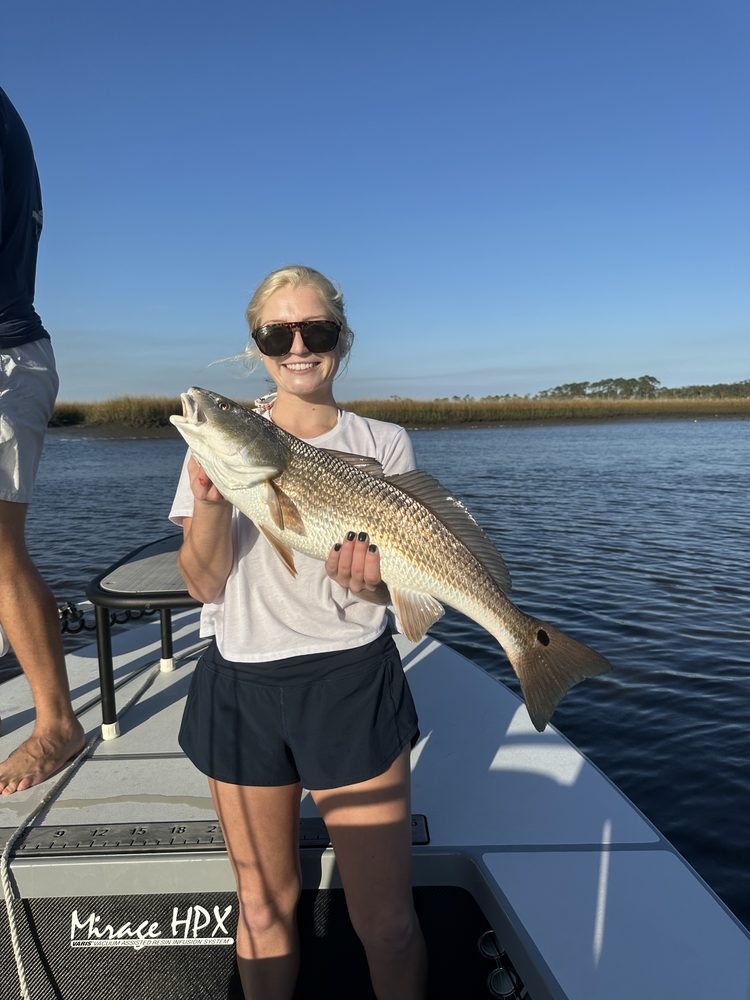 Angler on the skiff holding a spotted seatrout