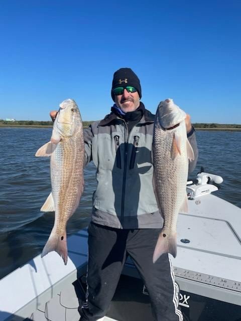Two anglers on the skiff with the day's redfish