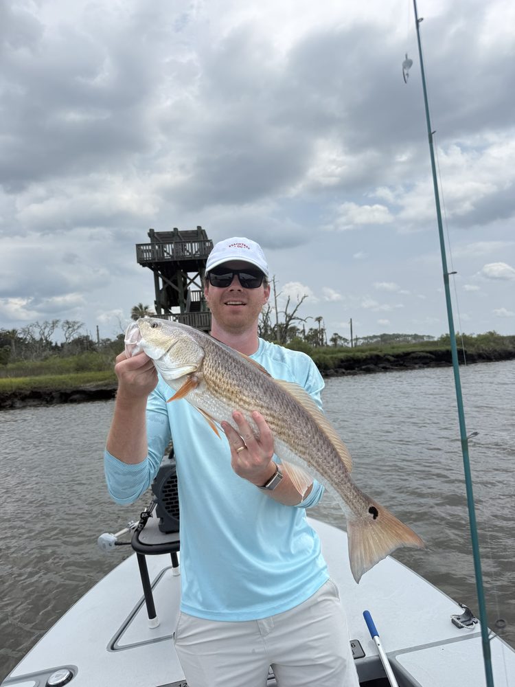 Angler holding a redfish beside the marsh