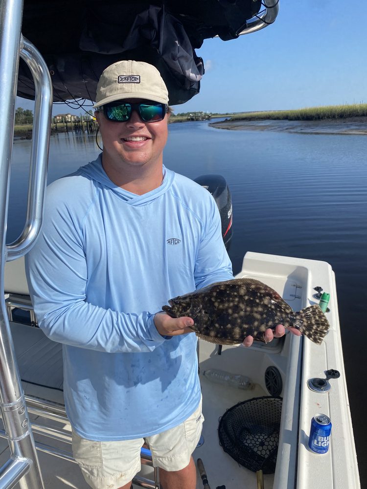 Angler on the skiff holding a flounder