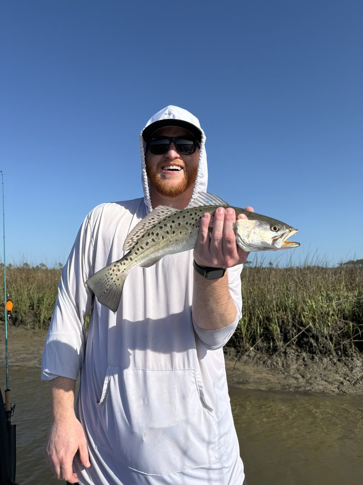 Angler on the bank holding a spotted seatrout