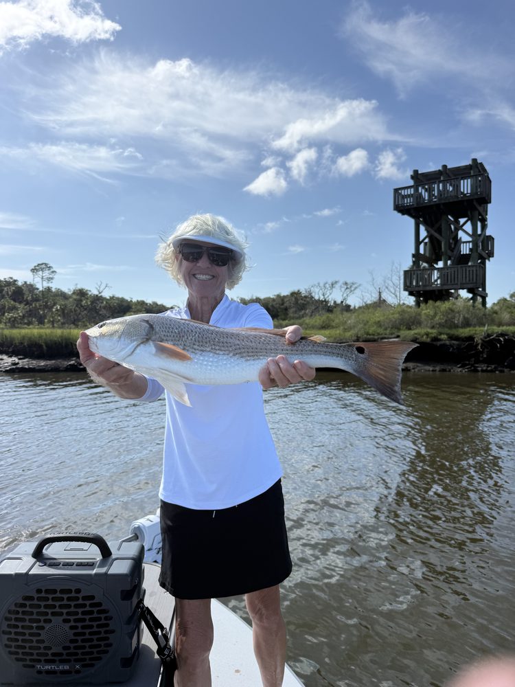 Angler holding a redfish in a marsh creek
