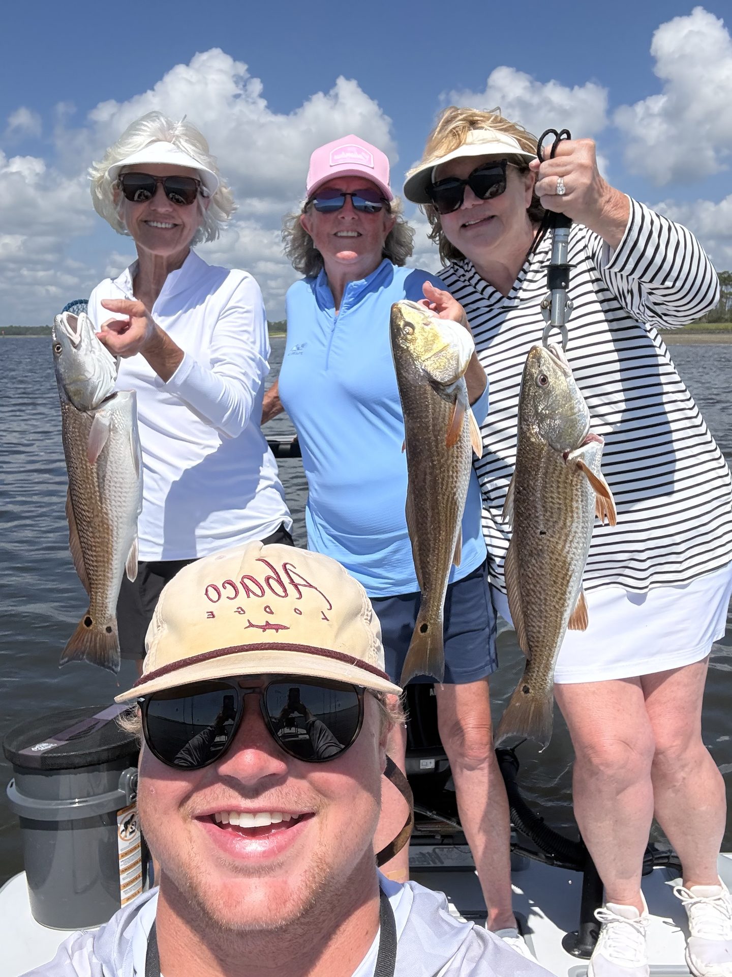 Captain Wills taking a selfie with three anglers holding redfish